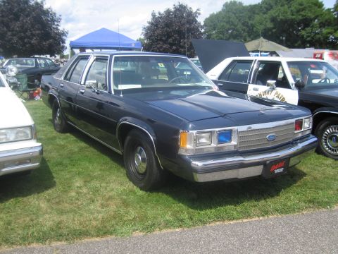1991 Ford LTD Crown Victoria - dark blue Ford LTD Crown Victoria four-door sedan parked on grass, with other classic cars and tents in the background.
