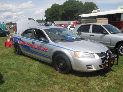 1991 Ford LTD Crown Victoria - silver sedan marked EMERGENCY SERVICE UNIT with blue striping, a front push bar and a rear-mounted equipment box sits on grass.