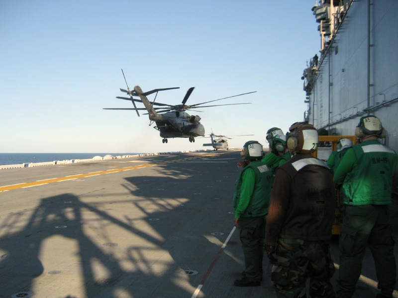 Large military helicopter hovering over a ship flight deck