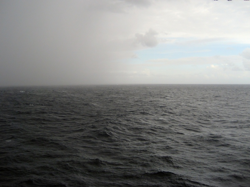 Overcast ocean horizon with a rain squall in the distance