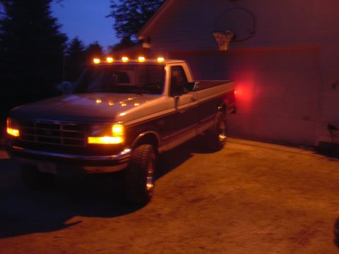 1996 Ford Crown Victoria - This Ford F-Series truck has cab lights illuminated and is parked near a garage at dusk.
