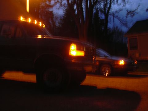 1996 Ford Crown Victoria - A dark truck with illuminated cab lights is parked near a house at dusk, with another car visible in the background.