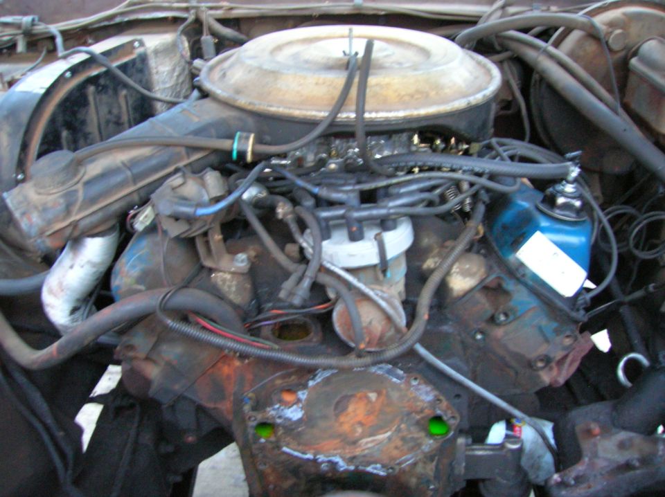 Close-up of a dirty engine bay with hoses and wires