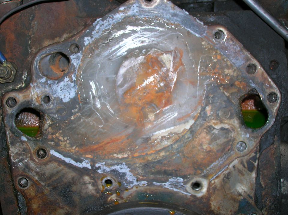 Engine block with water pump housing removed, showing corrosion and green coolant