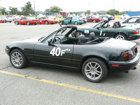 2001 Mercury Grand Marquis - A black convertible with racing numbers is parked in a lot full of vehicles.