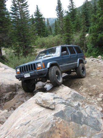 1995 Ford Bronco - Jeep Cherokee XJ navigates a rocky mountain path, its off-road capabilities.