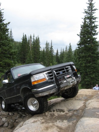 1995 Ford Bronco - A black Ford Bronco navigates a challenging rocky trail in a mountainous area.