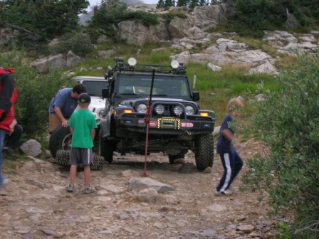 1995 Ford Bronco - Two Jeeps navigate a rocky trail with people around them.