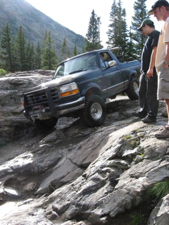 1995 Ford Bronco - A 1995 Ford Bronco tackles a challenging rocky trail with onlookers observing.