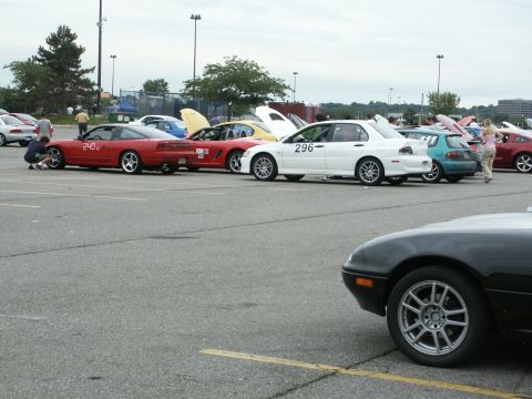 2001 Mercury Grand Marquis - A variety of cars are parked in a lot, with some people milling about near the vehicles.