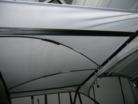 1995 Ford Bronco - The interior roof structure of a vehicle is visible, showing white fabric and black metal supports.