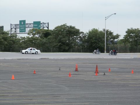 2001 Mercury Grand Marquis - A police car and two motorcycles are seen on a road with traffic cones in the foreground.