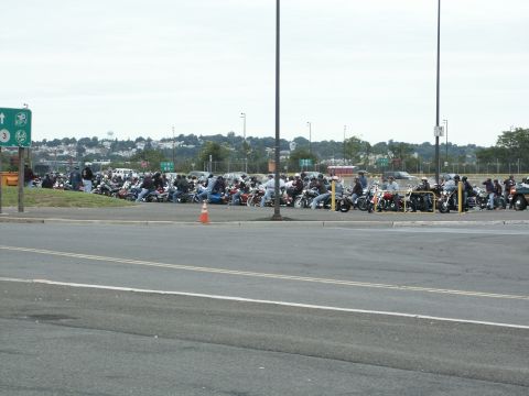 2001 Mercury Grand Marquis - A large group of motorcycles and riders gathered in an outdoor parking area on an overcast day.