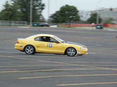 2001 Mercury Grand Marquis - A yellow coupe with racing decals is captured in motion on a track.