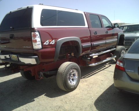 2000 Chevrolet Tahoe - This maroon pickup truck features a white camper shell and a 4x4 badge, seen from the rear.