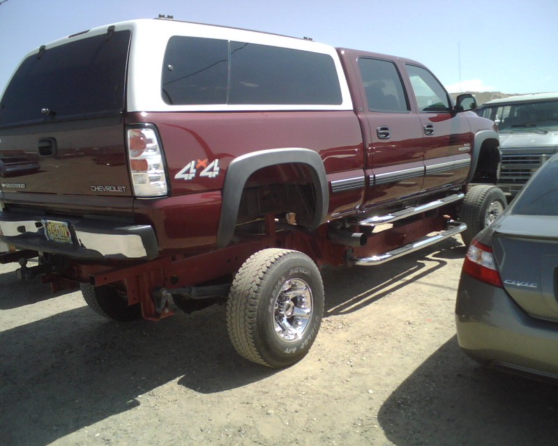 Maroon pickup truck with white camper shell, rear view, 4x4 badge