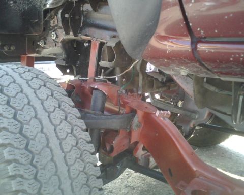 2000 Chevrolet Tahoe - Undercarriage view of a vehicle's suspension system and tire, with visible red painted frame parts.