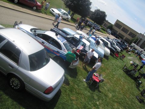 1991 Ford LTD Crown Victoria - Spectators mingle among police cars at an outdoor show, with a silver cruiser and an Emergency Service Unit car in the foreground.
