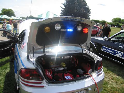 1991 Ford LTD Crown Victoria - raised trunk of a silver Emergency Service Unit car reveals stored equipment, with esu2550.com lettering and amber-blue lights above.