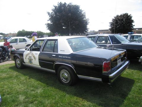 1991 Ford LTD Crown Victoria - black-and-white Highway Patrol Ford LTD Crown Victoria police sedan marked Safety and Service parked on grass at a car show.