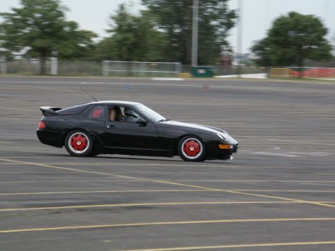2001 Mercury Grand Marquis - A black sports coupe with red wheels navigates a track, displaying the number 114 on its side.