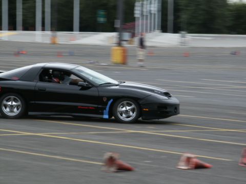 2001 Mercury Grand Marquis - A black Pontiac Firebird is seen on a paved course, possibly during a timed event.