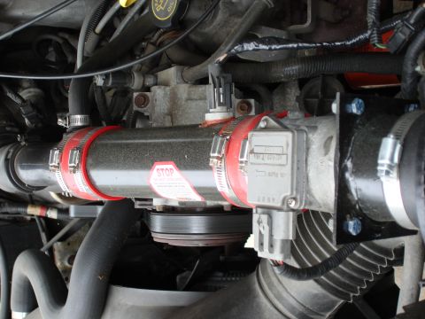 1994 Ford Bronco - Close-up view of engine components, including an intake tube and sensor, with visible text on a sticker.