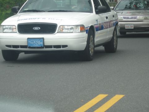 1991 Ford LTD Crown Victoria - white Ford Crown Victoria marked Sheriff's Dept drives on a road with another cruiser behind it.