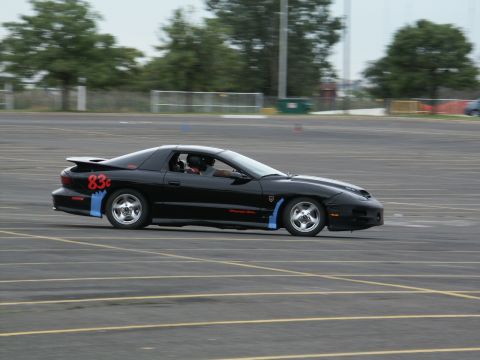 2001 Mercury Grand Marquis - A black Pontiac Firebird with racing decals is seen on a paved track during an event.