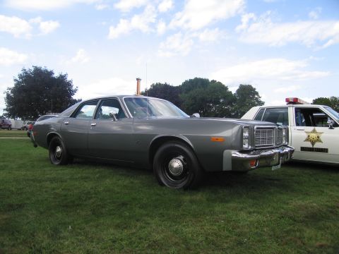 1991 Ford LTD Crown Victoria - Front-quarter view of a gray late-1970s Dodge four-door police sedan parked on grass next to a white sheriff cruiser at a car show.