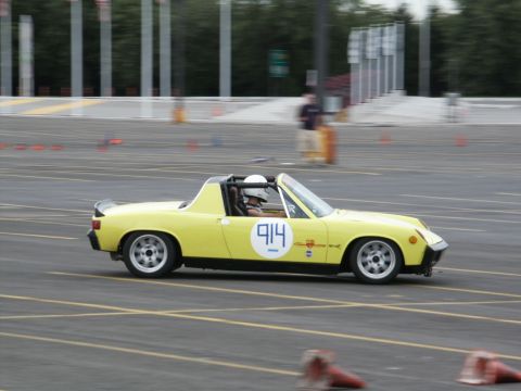 2001 Mercury Grand Marquis - A yellow Porsche 914 is seen on a race track with cones marking the course.