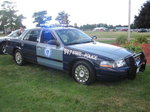 1991 Ford LTD Crown Victoria - blue-and-gray State Police Ford Crown Victoria marked 947 with front push bar, parked on grass at an outdoor event.