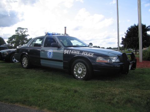 1991 Ford LTD Crown Victoria - two-tone State Police Ford Crown Victoria numbered 947 with roof light bar and push bar, displayed on a grassy lawn.