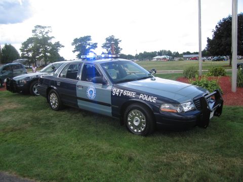 1991 Ford LTD Crown Victoria - blue-and-gray State Police Crown Victoria marked 947 with push bar parked on grass next to other cruisers at a show.