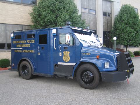 1991 Ford LTD Crown Victoria - blue Springfield Police Department Tactical Operations armored truck with reinforced bumper, parked outside a building.