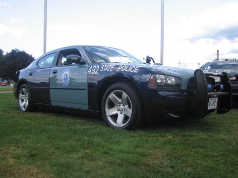1991 Ford LTD Crown Victoria - two-tone State Police Dodge Charger marked 492 with front push bar parked on grass beside another cruiser.