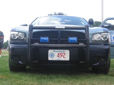 1991 Ford LTD Crown Victoria - Head-on view of a dark Dodge Charger police car with push bar, blue lights, and a Massachusetts official plate reading 492.