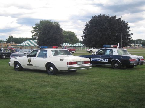 1991 Ford LTD Crown Victoria - white Chevrolet sheriff sedan parked rear-to-front beside a dark blue North Haven Police sedan on a grassy show field.