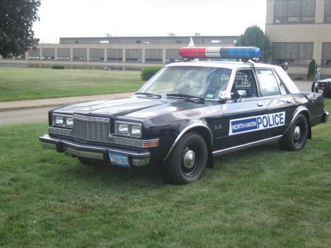 1991 Ford LTD Crown Victoria - black-and-white North Haven Police sedan with a roof lightbar sits front-quarter on a grassy lawn by a building.