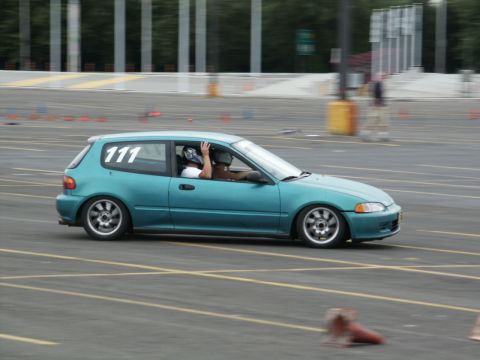 2001 Mercury Grand Marquis - A teal hatchback with racing numbers navigates a course, with a driver and passenger wearing helmets.