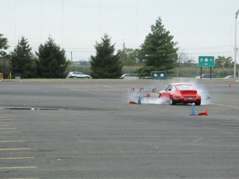 2001 Mercury Grand Marquis - A red sports car is seen drifting around a course of cones in an open parking lot.