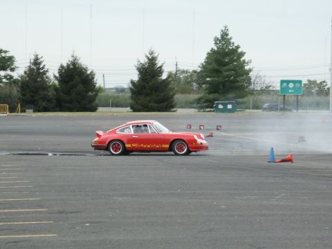 2001 Mercury Grand Marquis - A red Porsche 911 is seen drifting on an asphalt course with cones and trees in the background.