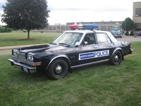1991 Ford LTD Crown Victoria - Side profile of a black-and-white North Haven Police sedan with a roof lightbar parked on a grassy field.