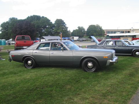 1991 Ford LTD Crown Victoria - Side profile of a gray four-door sedan with black steel wheels parked on grass at a vehicle show.