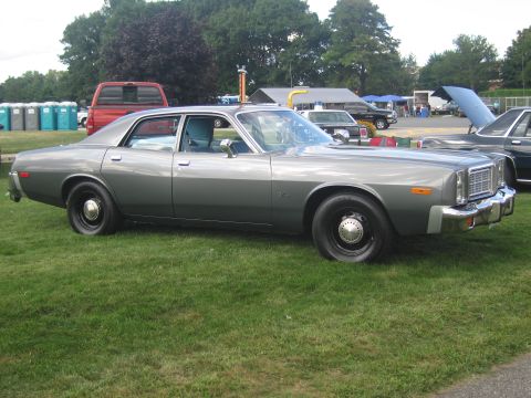 1991 Ford LTD Crown Victoria - Side profile of a silver-gray four-door sedan with black steel wheels parked on grass at an outdoor car show.