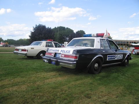 1991 Ford LTD Crown Victoria - Rear three-quarter view of a black-and-white North Haven Police sedan parked next to a white sedan on a lawn.