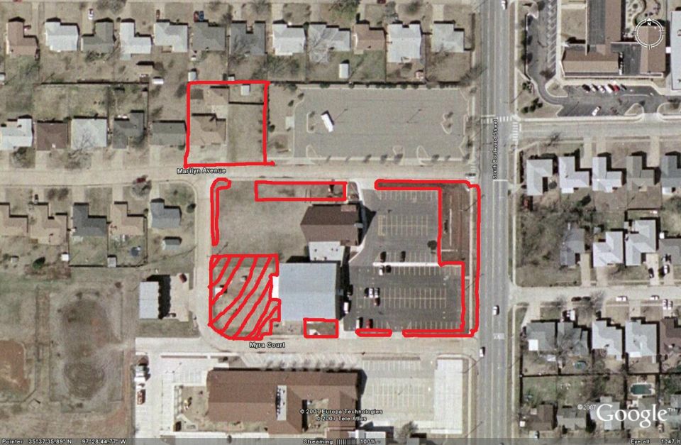 Aerial view of a neighborhood with red outlines on properties and streets, showing houses and parking lots