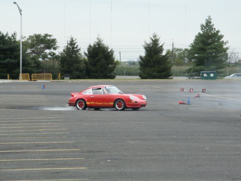 2001 Mercury Grand Marquis - A red Porsche 911 Carrera is seen drifting on a paved surface, with cones marking a course.