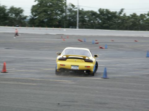 2001 Mercury Grand Marquis - Yellow Mazda RX-7 navigates an autocross course marked by cones.