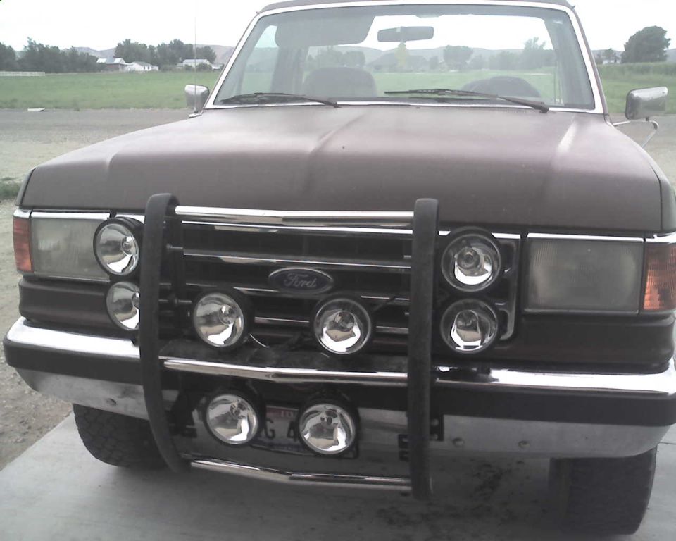 Dark brown Ford truck front view with a chrome grille guard and multiple round lights